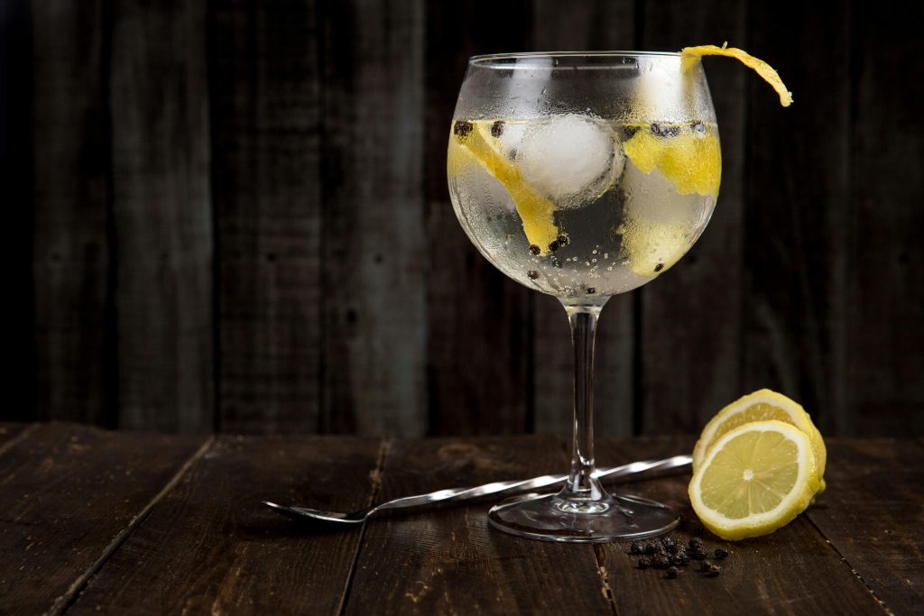 pexels-photo-616836-616836 A close-up of a refreshing gin cocktail with lemon slices on a rustic wooden table, perfect for summer.